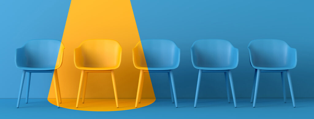 A row of blue chairs, with a yellow light shining on one of them.